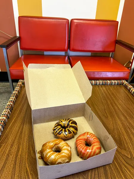 Dough House in Black Mountain, North Carolina Gluten Free and vegan donuts with strawberry, chocolate, and vanilla frosting in takeaway container on table
