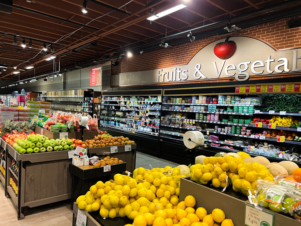 Earth Fare Asheville NC with inside of grocery store's produce section with barrels full of fruits and veggies and stocked shelves under fruit and veggie sign