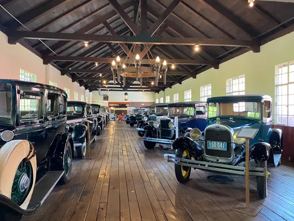 Estes-Winn Antique Car Museum in Asheville with two rows of old cars on wooden showroom floor with wooden hanging chandeliers