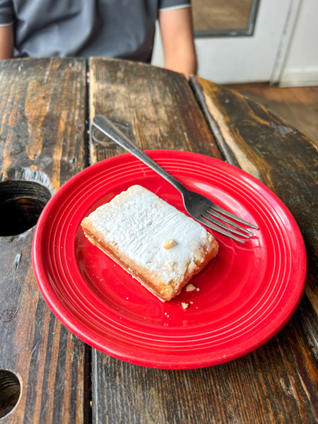 Odds Cafe Asheville NC gluten free and vegan dessert with white powdery top on red plate with fork on brown table