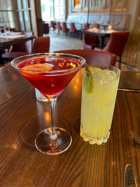 Posana Restaurant Asheville NC red cocktail in martini glass and yellow cocktail in tall glass on brown table