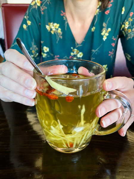 Soba Sushi and Noodles Weaverville NC Tea with white woman in green flower top holding large glass filled with ginger and honey tea