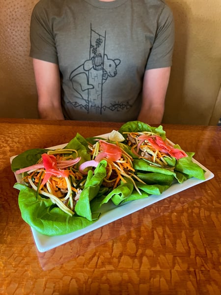 Stoney Knob Cafe Weaverville Thai Pork Wraps with bright green lettuce, pink ginger, pork, picked onions, and carrots on white plate
