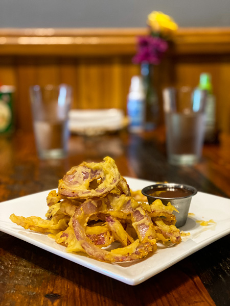 Thai Pearl Asheville Restaurant with Thai fried onion rings on a small appetizer dish and glasses of water in the background