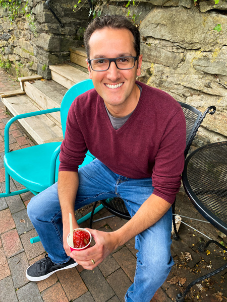 The Hop Ice Cream Cafe in Black Mountain NC with white brunette male in red sweater and jeans sitting in chair and eating ice cream