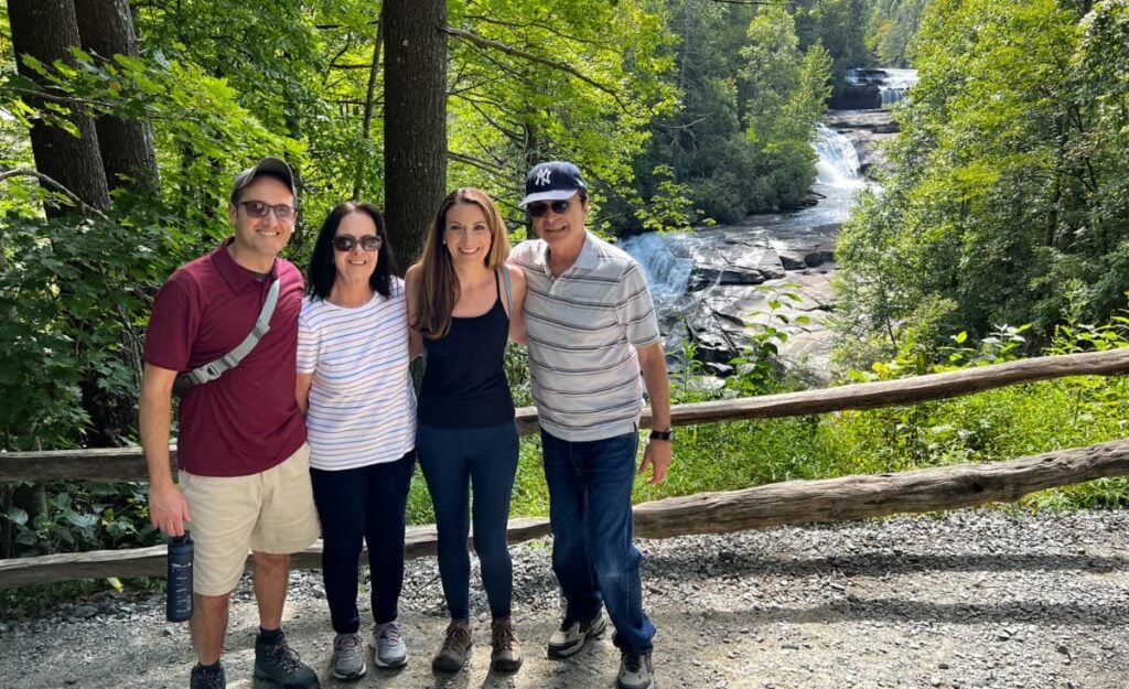 family of 4 in front of Triple Falls waterfall at DuPont