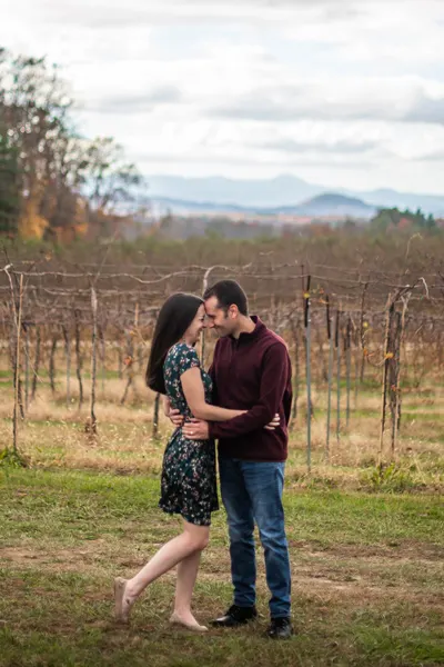 Asheville in October Marked Tree Vineyard with white brunette and female in front of vineyard; she is wearing a green dress and he is in a red sweater and jeans