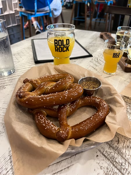 Bold Rock Cidery Asheville Brunch with two pretzels and glass of yellow cider on table