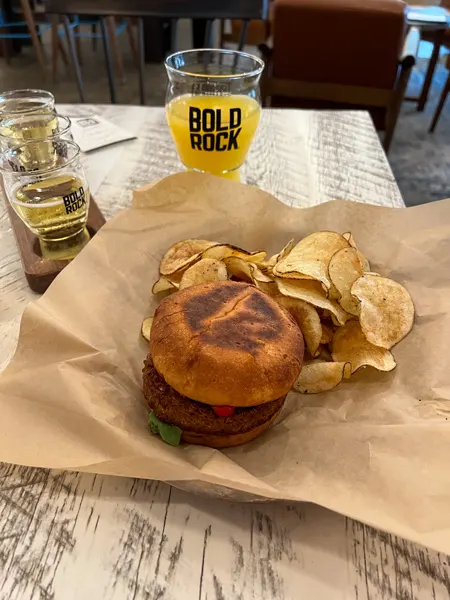 Bold Rock Cidery Asheville Gluten-free burger with chips on side and cider mimosas behind it on table