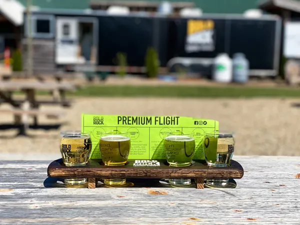 Bold Rock Cidery Asheville Mills River NC premium flight with four flight glasses filled with golden and yellow colored cider outside on picnic table