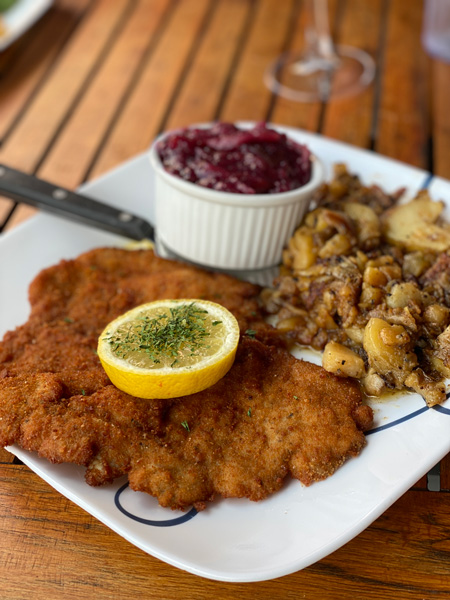 Haus Heidelberg German Restaurant Hendersonville with breaded schnitzel on plate with fried potatoes and red cabbage garnished with lemon slice