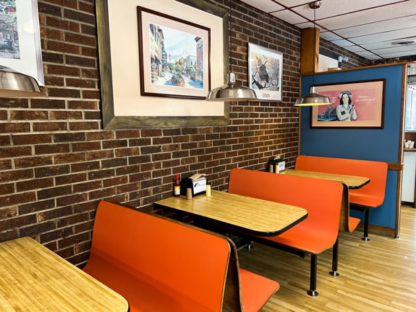 Hot Dog World Hendersonville North Carollina with orange booths with tables against a brick wall
