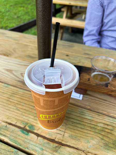 Jeter Mountain Farm Cider Slushie Hendersonville NC with slushie in to-go cup with black straw on a picnic table