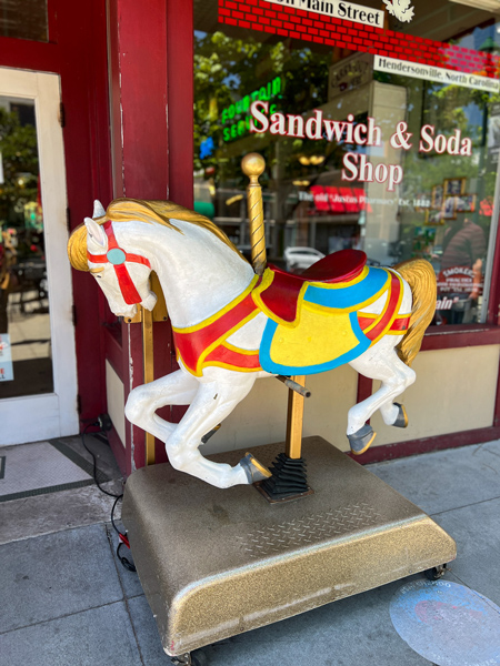 Mikes On Main Restaurant Hendersonville NC with white carousel horse in front of window advertising sandwiches and subs 