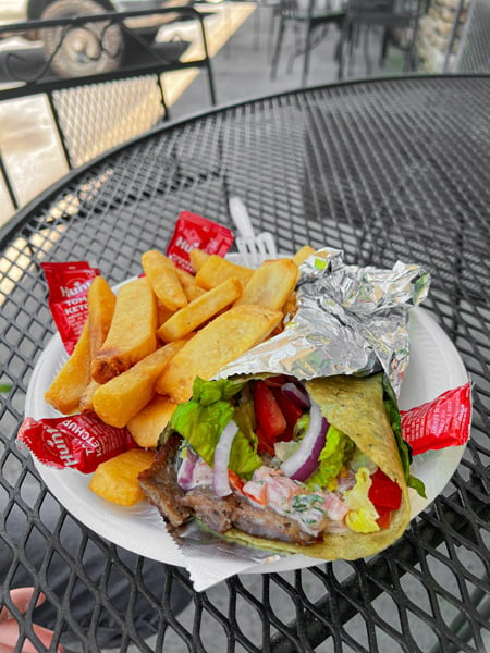 Pita Express Hendersonville NC Pita in foil with meat, lettuce, tomato and side of French fries on outdoor patio table
