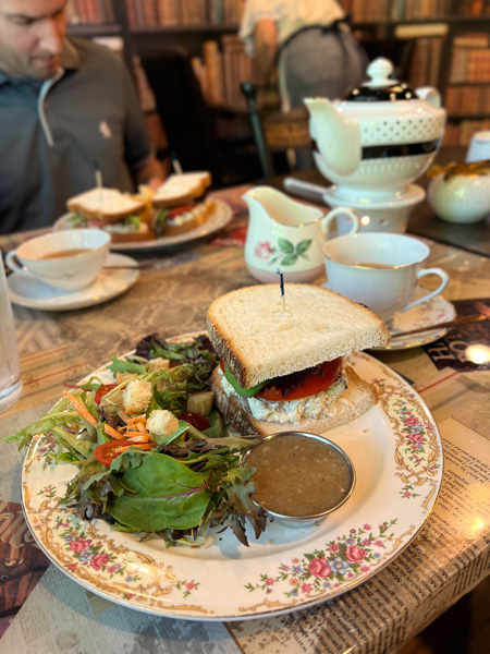 The Book and Bee Cafe and Tearoom Restaurant Hendersonville NC with fancy plate filled with salad and half of a chicken salad sandwich with teapot and tea in background