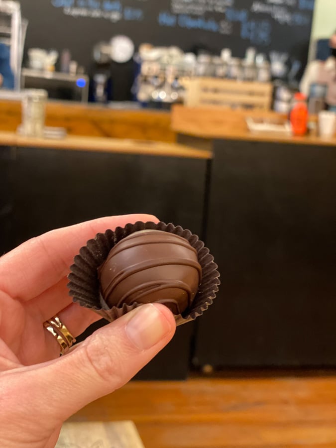Asheville Chocolate Vegan Truffle with white hand holding up truffle over counter