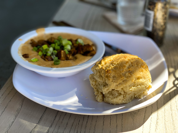 Biscuit Head Asheville Breakfast with biscuit and vegan cheese gravy and sausage on white plate