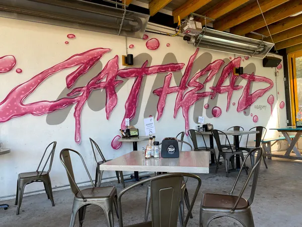 Biscuit Head South Asheville location with cathead mural in pink lettering by Gus Cutty