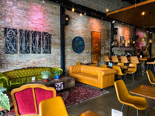 Bottle Riot Wine Bar Asheville with yellow and green couches, purple rug, and pink chair with bar
