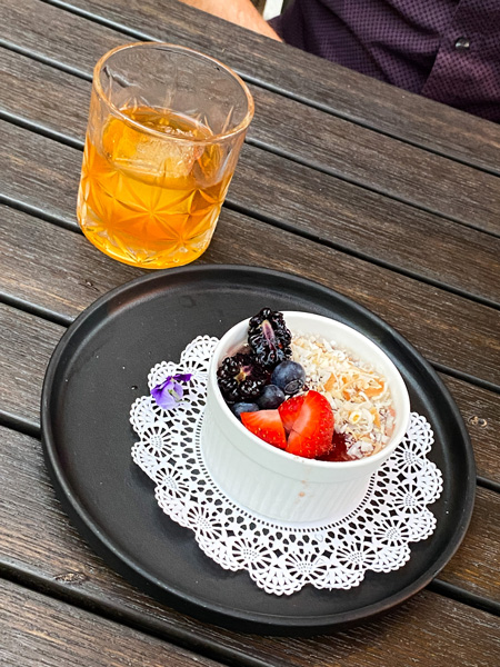 Dessert with strawberries and blueberries next to orange-ish cocktail at Crave Dessert Bar in Asheville