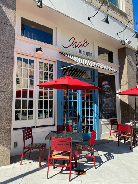 Isa's French Bistro Breakfast Brunch in Downtown Asheville with blue doors, white facade, and red tables with umbrellas