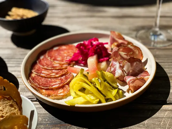 Leos House Of Thirst Charcuterie with cured meats, pickles, crackers and wine glass