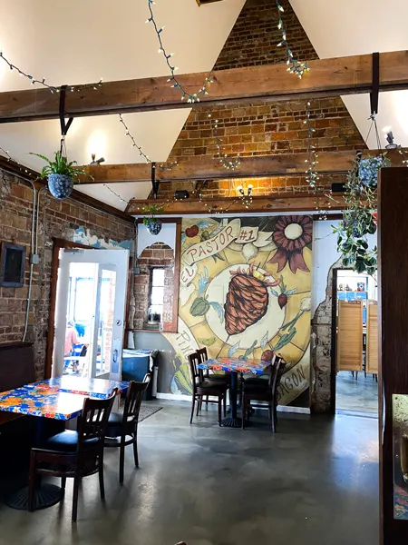 Mamacita's Taco Temple Asheville NC with inside of restaurant that looks like a church with mural on the wall, wood beam ceilings with lights, and dining tables and chairs