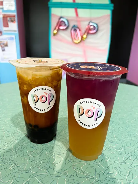 Pop Bubble Tea Asheville North Carolina with two unopened bubble teas on green table and one boba is yellow and pink and the other is white and brown with tapioca balls