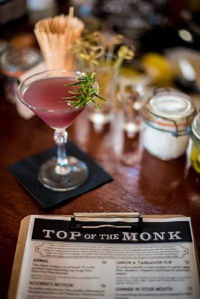 Top Of The Monk Rooftop Bar Asheville NC with picture of menu and pink cocktail garnished with rosemary