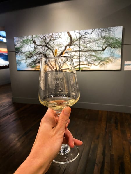 Walls Wine Bar Asheville NC with white wine glass in front of Benjamin Walls artwork of a tree