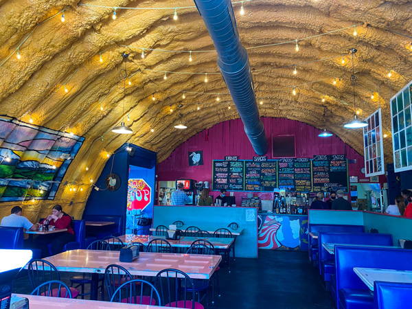 White Duck Taco Shop River Arts District Asheville, NC with menu of tacos, big wall, yellow ceilings with lights, and colorful tables