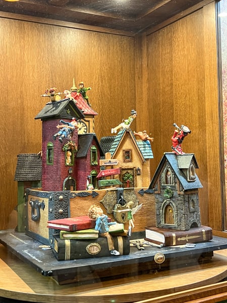 The Omni Grove Park Inn Annual National Gingerbread House Competition 2023 winner in rotating display case with gingerbread house with Peter Pan scene with houses, characters, and books