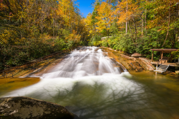 Sliding Rock Pisgah National Forest NC with fall foliage, lifeguard platform, and waterfall with railing going up left side of rock