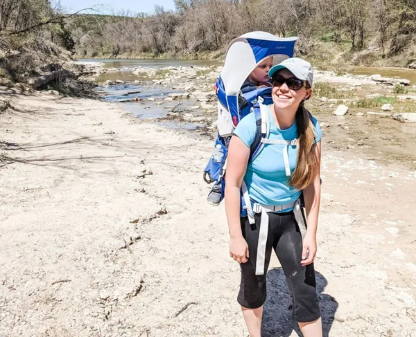 Tori Curran Explore With Tori white woman with long dirty blonde hair in light blue shirt with baby in hiking pack on back