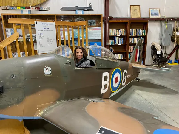 Western North Carolina Air Museum in Hendersonville NC with white brunette woman in old plane with library of plane books in the background
