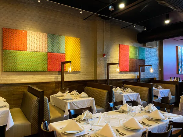 Andaaz Restaurant in Biltmore Village in Asheville NC with colorful square pictures on walls, tables with white table cloths and folded napkins, and table and booth seating