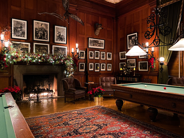 Biltmore Candlelight Christmas Evenings Tour with billiard room decorated with tree, lit fireplace, and garland 