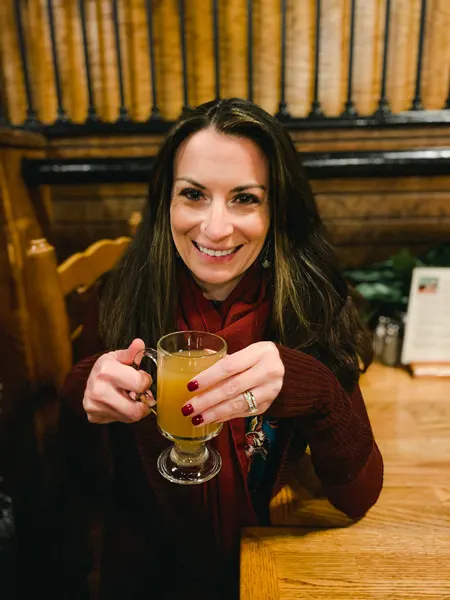 Biltmore Estate Christmas Dinner Stable Cafe with white brunette female in maroon sweater drinking a hot apple cider cocktail