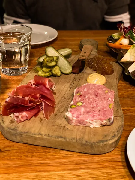 Charcuterie The Bull and Beggar Asheville, NC with two meats, brown jam, pickles and glass of water