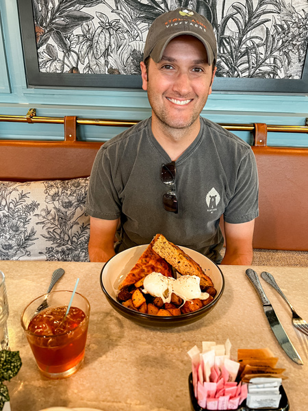 Gemelli Restaurant in Asheville Eggs and potatoes with gluten-free and vegan focaccia in bowl with white brunette male about to eat it 