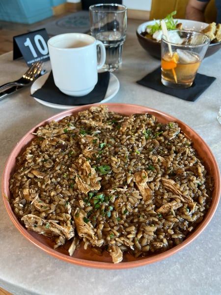 Gemelli Restaurant in Asheville NC mushroom and pulled pork Risotto dish with tea mug behind it