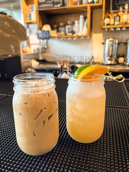 Haywood Common Asheville NC iced Latte and yellow orange cocktail with orange garnish in mason jars on bar top