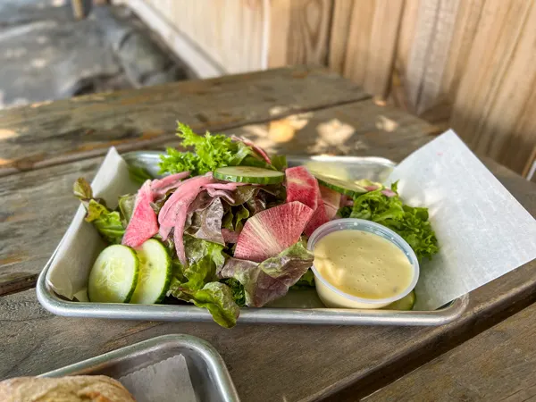 Haywood Common Asheville NC Salad in tin with red radishes, cucumber, and lemon vinaigrette on picnic table