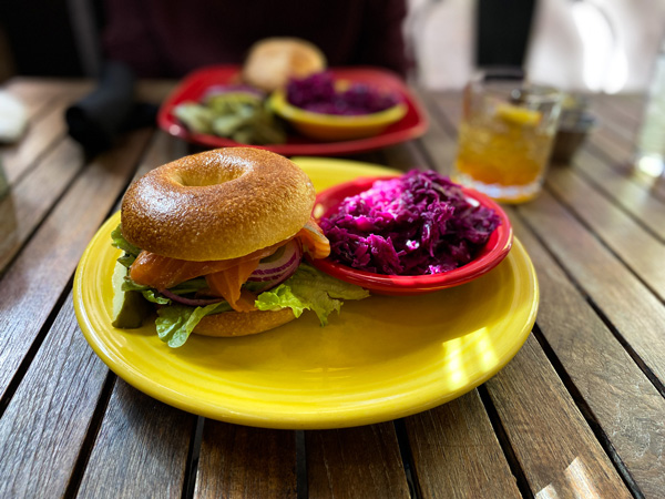 Lox Corner Kitchen Asheville NC Brunch with bagel on salmon on yellow plate with red slaw and cocktails