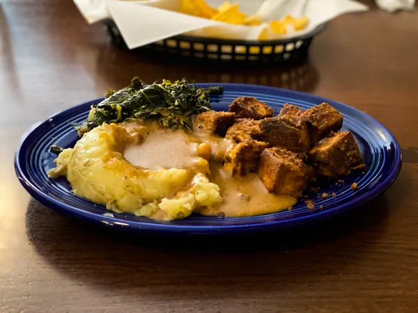 Rosettas Kitchen Vegan Asheville NC with blue plate filled with mashed potatoes, gravy, and kale