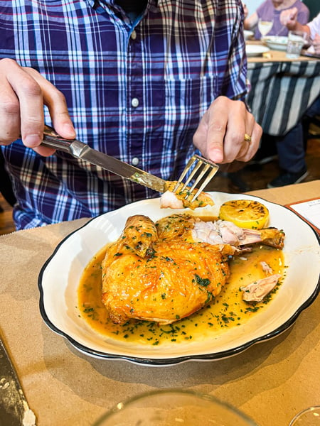 White male in purple plaid shirt cutting a half-roasted chicken at Tall John's Neighborhood Tavern in Asheville, NC