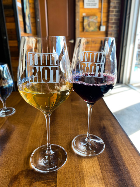 Bottle Riot Wine Bar River Arts District with red and white wine glass on table