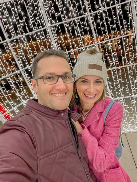 Christine and Tom, a white brunette male and female, taking a selfie at the Christmas Lights in Forest City, NC; they are standing in a giant ornament light display