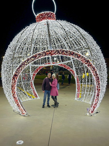 Forest City, NC famous Christmas Ornament in POPS with white brunette male and female in winter coats standing under it